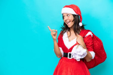 Anne Noel gibi giyinmiş genç İspanyol bir kadın mavi arka planda izole edilmiş bir çuvalı tutuyor. Çözümün ne olduğunu anlamak için parmağını kaldırıyor.