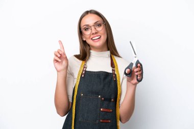 Genç terzi kadın beyaz arka planda izole edilmiş ve en iyinin işareti olarak parmağını kaldırıyor.