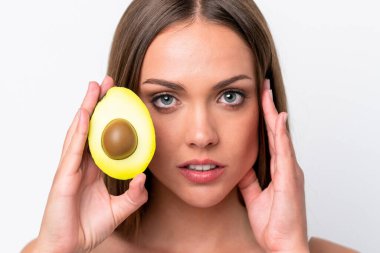 Beyaz arka planda avakado tutan beyaz bir kadın. Portreyi kapat