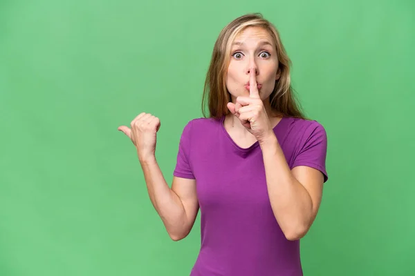 Young Blonde Woman Isolated Background Pointing Side Doing Silence Gesture — Stock Photo, Image
