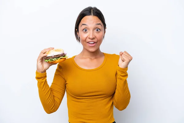 Młoda Latynoska Kobieta Trzyma Hamburgera Białym Tle Świętując Zwycięstwo Pozycji — Zdjęcie stockowe