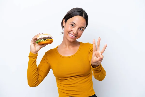 Młoda Latynoska Kobieta Trzyma Hamburgera Białym Tle Szczęśliwa Liczy Trzy — Zdjęcie stockowe