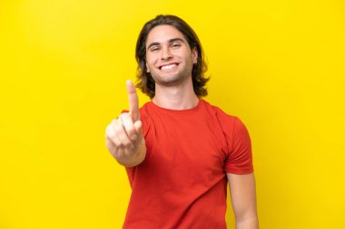 Sarı arka planda izole edilmiş beyaz yakışıklı adam parmağını kaldırıyor ve gösteriyor.