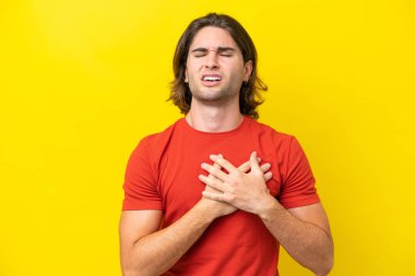 Sarı arka planda izole edilmiş beyaz yakışıklı bir adam. Kalbinde bir ağrı var.