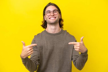 Beyaz tenli yakışıklı adam sarı arka planda soyutlanmış gururlu ve kendini beğenmiş.