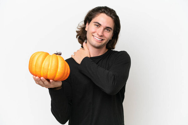 Young handsome man holding a pumpkin isolated on white background laughing