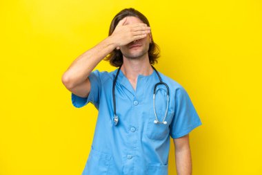 Genç cerrah beyaz adam sarı arka planda tek başına, gözleri elleriyle kapatıyor. Bir şey görmek istemiyorum.