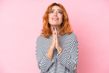 Pembe arka planda izole edilmiş genç beyaz kadın avuç içlerini bir arada tutuyor. İnsan bir şey ister.