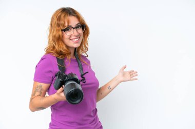 Beyaz arka planda izole edilmiş genç fotoğrafçı beyaz kadın davet etmek için ellerini yana uzatıyor.
