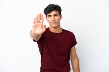 Beyaz arka planda izole edilmiş genç Arjantinli adam dur hareketi yapıyor.