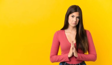 İzole edilmiş sarı arka planı olan Brezilyalı genç kız avuç içlerini bir arada tutuyor. İnsan bir şey ister.