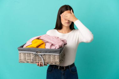 Elinde çamaşır sepeti tutan Brezilyalı genç bir kız mavi arka planda tek başına gözlerini kapatıyor. Bir şey görmek istemiyorum.