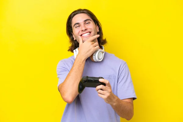 若いですハンサムなCaucasian男遊びますとともにAビデオゲームコントローラ上の孤立した上の黄色の背景幸せと笑顔 — ストック写真