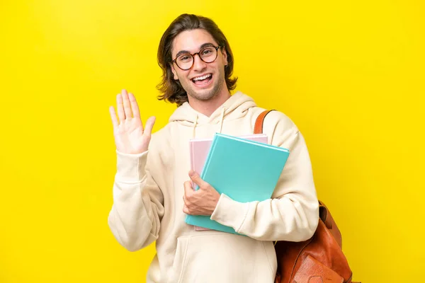 Jovem Estudante Bonito Homem Isolado Fundo Amarelo Saudando Com Mão — Fotografia de Stock