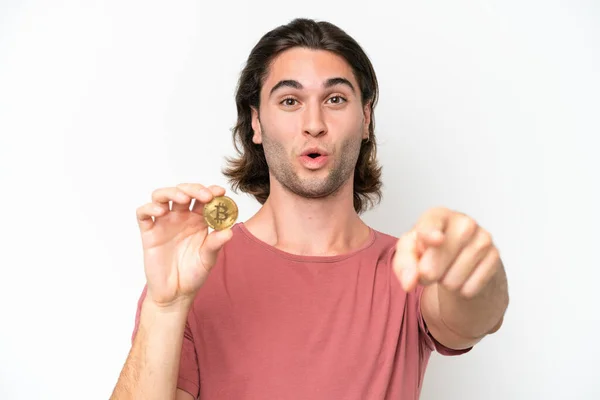Νεαρός Όμορφος Άντρας Κρατώντας Ένα Bitcoin Απομονωμένο Λευκό Φόντο Έκπληκτος — Φωτογραφία Αρχείου