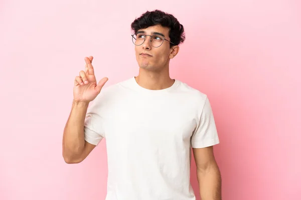 Jonge Argentijnse Man Geïsoleerd Roze Achtergrond Met Vingers Kruisen Wensen — Stockfoto