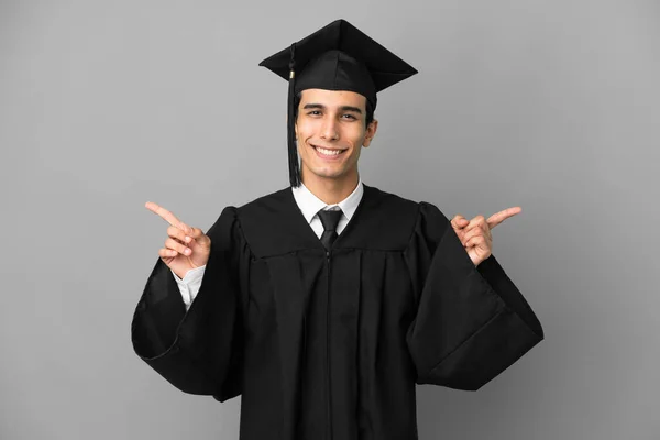 若いアルゼンチンの大学の卒業生は ラテン語と幸せな指を指して灰色の背景に隔離されました — ストック写真