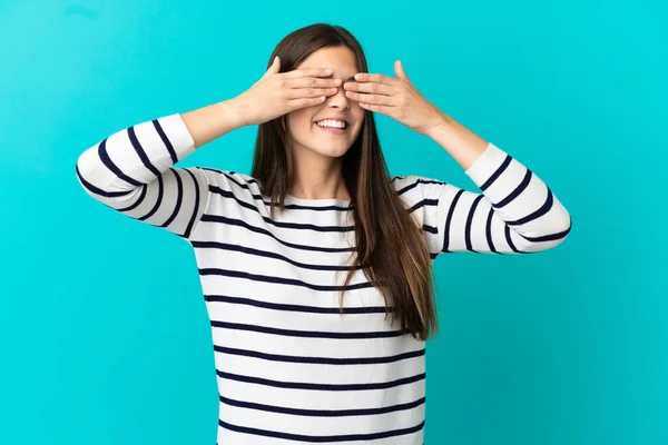 Teenager Brazilian girl over isolated blue background covering eyes by hands and smiling