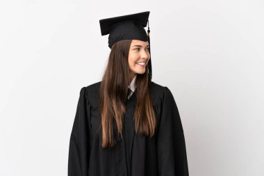 Genç Brezilyalı üniversite mezunu izole edilmiş beyaz arka planda yan bakıp gülümsüyor.