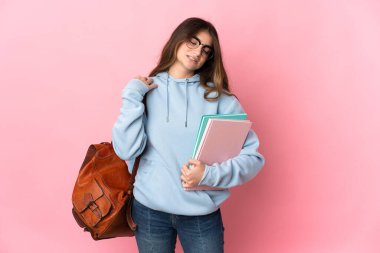 Pembe arka planda izole edilmiş genç bir bayan omuz ağrısından muzdarip.