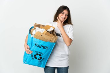 Elinde kağıt dolu bir geri dönüşüm çantası olan genç bir kadın beyaz arka planda izole edilmiş mutlu ve gülümsüyor.