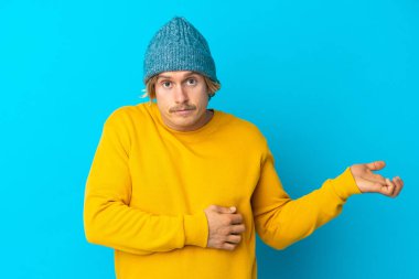 Mavi arka planda izole edilmiş yakışıklı sarışın adamın şüpheleri var.