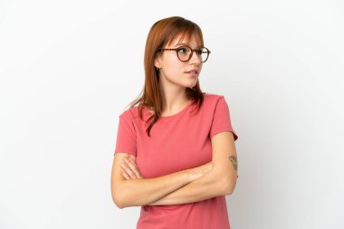 Kızıl saçlı kız beyaz arka planda izole edilmiş, kollarını çapraz tutuyor.