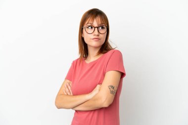 Kızıl saçlı kız, beyaz arka planda izole edilmiş. Omuzlarını kaldırırken şüpheli hareketler yapıyor.