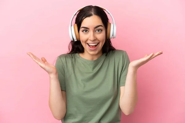 Jonge Kaukasische Vrouw Geïsoleerd Roze Achtergrond Verrast Luisteren Muziek — Stockfoto