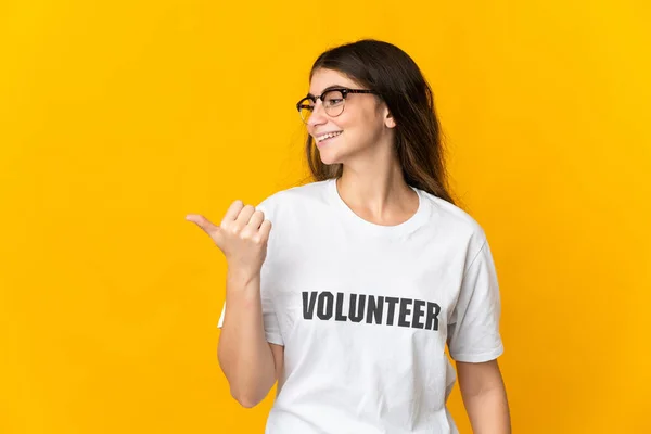 Mujer Joven Voluntaria Aislada Sobre Fondo Amarillo Apuntando Hacia Lado — Foto de Stock