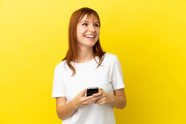 Redhead Κορίτσι Απομονώνονται Κίτρινο Φόντο Χρησιμοποιώντας Κινητό Τηλέφωνο Και Κοιτάζοντας — Φωτογραφία Αρχείου
