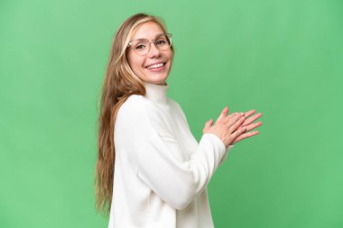 Genç sarışın kadın, izole edilmiş arka planı alkışlıyor.