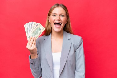 Kafkasyalı genç bir kadın elinde para tutuyor. Kırmızı arka planda, şaşırmış bir yüz ifadesi var.