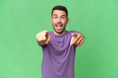 Soyutlanmış geçmişi olan yakışıklı beyaz bir adam şaşırmış ve ön tarafı işaret ediyor.