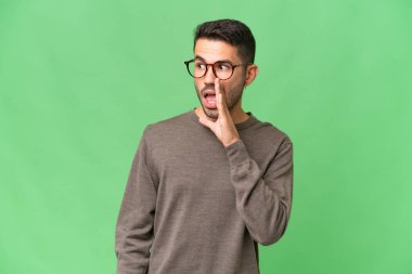 Genç, yakışıklı, beyaz, soyutlanmış bir adam. Yan tarafa bakarken sürpriz bir jest yapıp fısıldıyor.