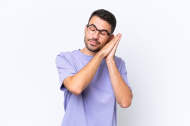 Beyaz arka planda izole edilmiş genç beyaz bir adam uyku jesti yapıyor.