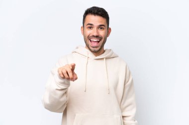 Beyaz arka planda izole edilmiş genç beyaz adam şaşırmış ve ön tarafı işaret ediyor.