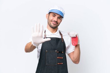Kasap beyaz önlük giymiş ve izole edilmiş beyaz arka planda taze et servisi yapan beş parmaklı beyaz adam.