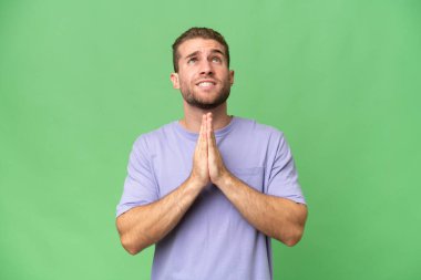 Yeşil krom arka planda izole edilmiş yakışıklı beyaz adam avuç içlerini bir arada tutuyor. İnsan bir şey ister.