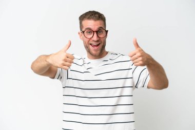 Beyaz arka planda izole edilmiş yakışıklı beyaz bir adam baş parmak hareketi yapıyor.