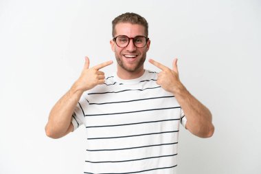 Beyaz arka planda izole edilmiş yakışıklı beyaz bir adam baş parmak hareketi yapıyor.