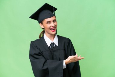 Genç üniversite mezunu beyaz bir kadın izole edilmiş arka planda gülümserken bir fikir sunuyor.