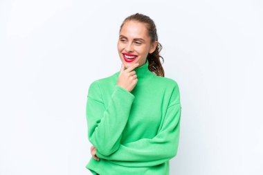 Beyaz arka planda izole edilmiş genç beyaz kadın yan bakıyor ve gülümsüyor.