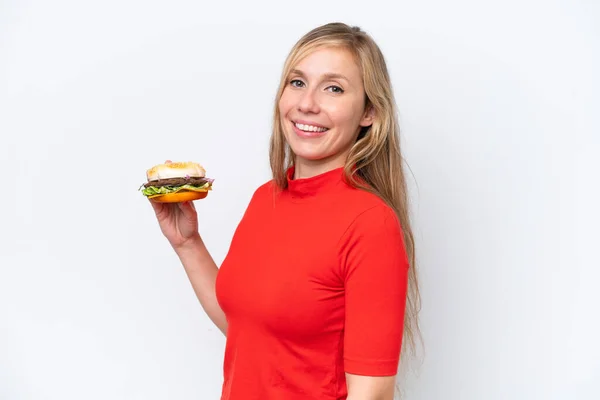 Fiatal Szőke Kezében Egy Burger Elszigetelt Fehér Háttér Mosolygós Sokat — Stock Fotó