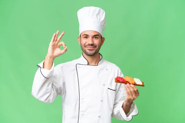 Junger Kaukasischer Koch Hält Ein Sushi Über Isoliertem Hintergrund Und — Stockfoto