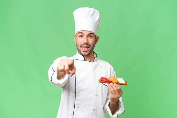 Junger Kaukasischer Koch Hält Überrascht Ein Sushi Über Isolierten Hintergrund — Stockfoto