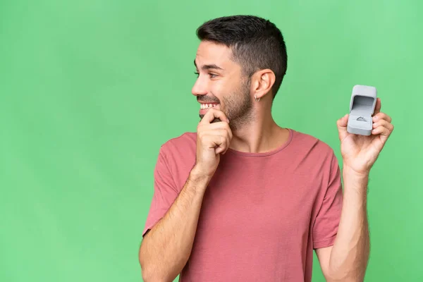 年轻英俊的高加索男人带着订婚戒指 带着孤立的背景 思考着一个想法 环顾四周 — 图库照片