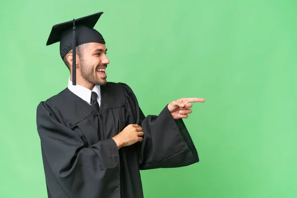 Νεαρός Απόφοιτος Πανεπιστημίου Πάνω Από Απομονωμένο Υπόβαθρο Δείχνοντας Δάχτυλο Στο — Φωτογραφία Αρχείου