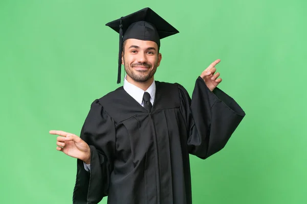 Νεαρός Απόφοιτος Πανεπιστημίου Άνθρωπος Πάνω Από Απομονωμένο Υπόβαθρο Δείχνοντας Laterals — Φωτογραφία Αρχείου