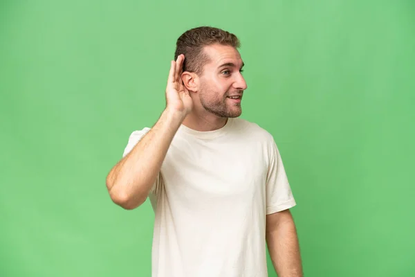 Mladý Pohledný Běloch Izolovaný Zeleném Chroma Pozadí Něco Poslouchá Tím — Stock fotografie